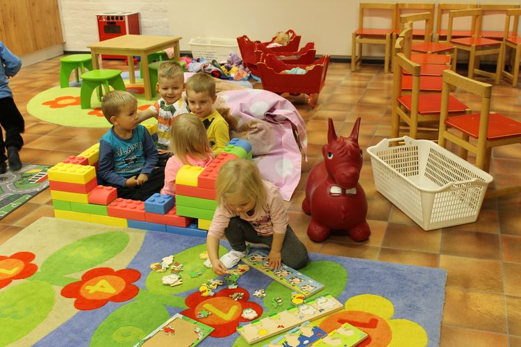 kuusi lasta leikkii päiväkerhossa ja ovat rakentaneet linnan isoista legoista.